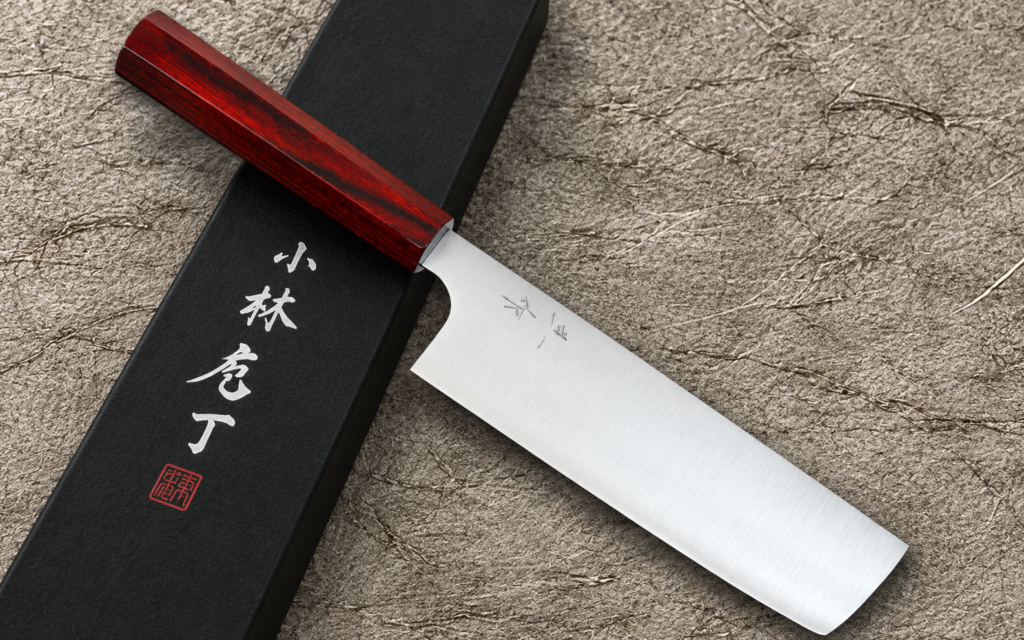 Kei Kobayashi R2/SG2 Nakiri 165mm with a red lacquered wooden handle resting diagonally across a black presentation box on a textured gray background.