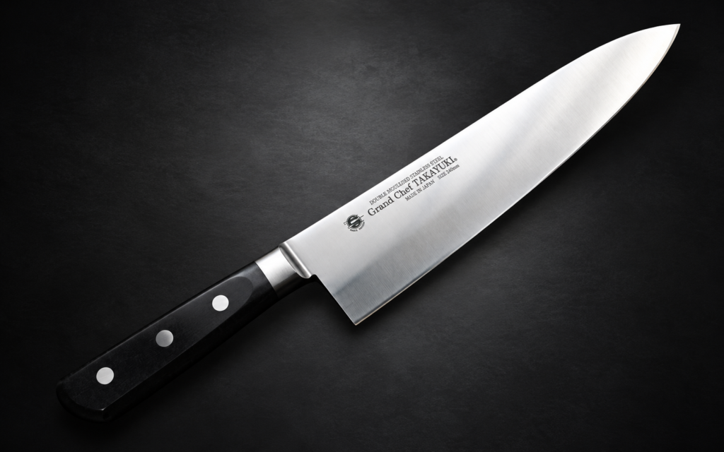 Sakai Takayuki Grand Chef 240mm gyuto knife displayed diagonally on a dark textured background, with a polished stainless steel blade and a black three-rivet handle.