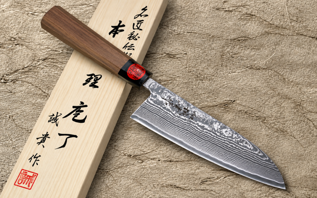 Shigeki Tanaka R2/SG2 Damascus Santoku 165mm with a dark wooden handle resting diagonally across a light wooden presentation box on a textured beige background.