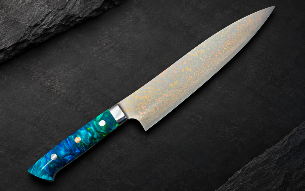 Takeshi Saji VG10 Colored Damascus Gyuto 210mm with a blue-green stabilized hybrid wood handle resting diagonally on a dark stone surface.